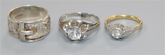 An 18ct gold, platinum and illusion set solitaire diamond ring, a 9ct white gold ring and a white metal buckle ring.